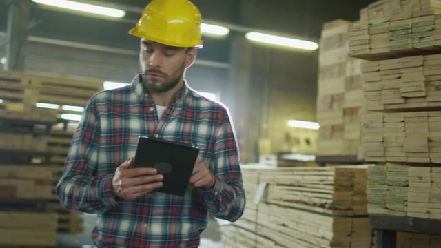 Worker is using a tablet computer in lumber factory warehouse. Shot on RED Cinema Camera.