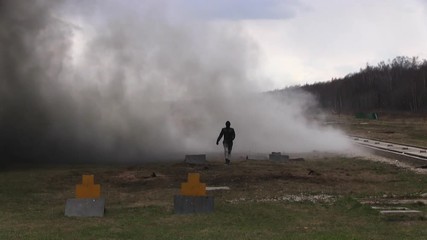 Stunt girl in a fiery explosion. Slow motion. Beautiful girl stunt runs across the field through the explosions and fire.