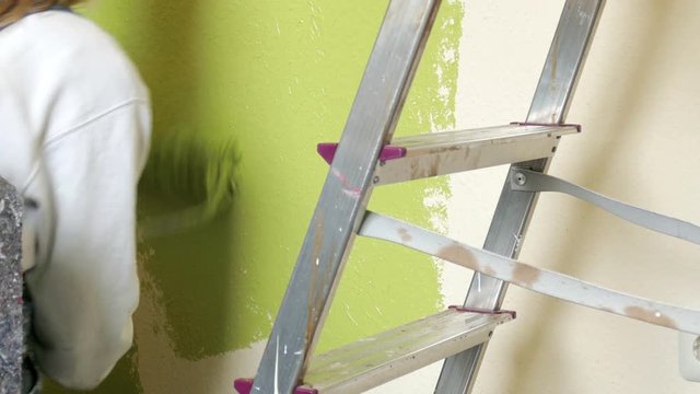 painter sweeps the walls with green paint
