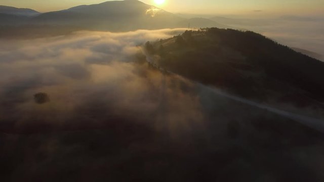 Aerial - Flying over the clouds at sunrise in the mountain 