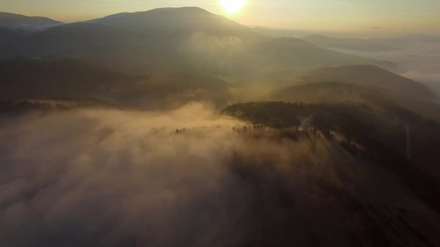 Aerial - Flying over the clouds at sunrise in the mountain 
