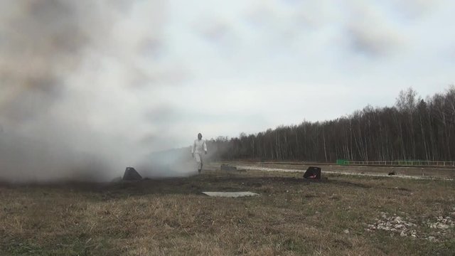 Stunt girl in a fiery explosion. Slow motion. Beautiful girl stunt runs across the field through the explosions and fire.