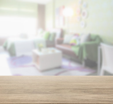 wooden table top with blur of colorful bedroom with brown sofa
