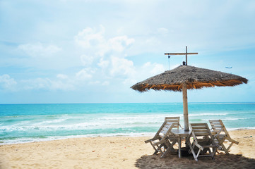 Obraz na płótnie Canvas The beach with Palapa hut beach sun roof and chairs nearby airpo