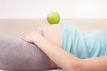Cute pregnant woman is relaxing on sofa