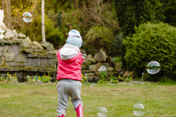 dziecko bawi się bańkami mydlanymi w ogrodzie
