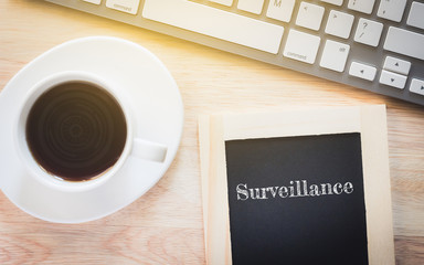 Concept Surveillance message on wood boards. A keyboard and a glass coffee table.Vintage tone.