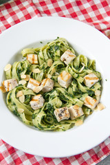 Tagliatelle with spinach and grilled salmon, fabric chequered, gray background, white plate.
