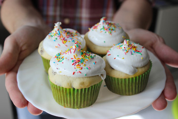 vanilla cupcakes with white cream and colorful decoration
