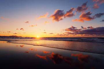 sunset on beach with cloud reflections