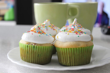 vanilla cupcakes with white cream and colorful decoration