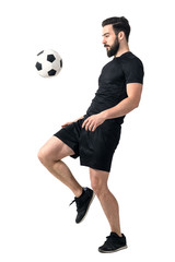 Side view of football or futsal player juggling ball with his knee. Full body length portrait...