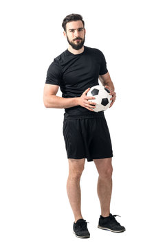 Confident soccer of futsal player holding ball with daring look at the camera. Full body length portrait isolated over white background.