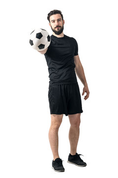 Football or soccer player holding and offering ball to a camera. Challenge concept. Full body length portrait isolated over white background.