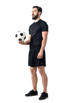 Football or soccer futsal player holding ball in one hand looking up. Full body length portrait isolated over white background.