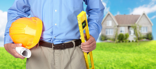 Hands of construction worker with helmet and level.
