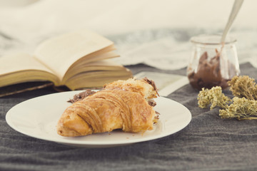 A fresh croissant over plate with chocolate to eat in a cozy spring morning