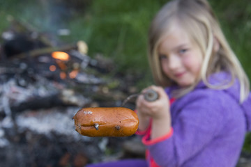 Girl Roasting and Eating Sausage Cooked On Camp Fire 