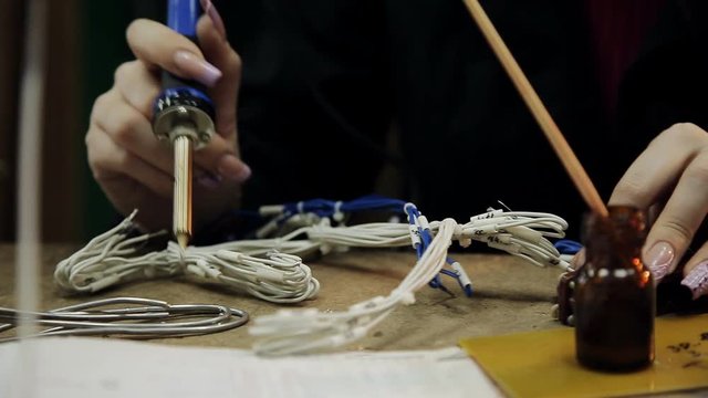 girl in a repair lab solder the cable to the connector