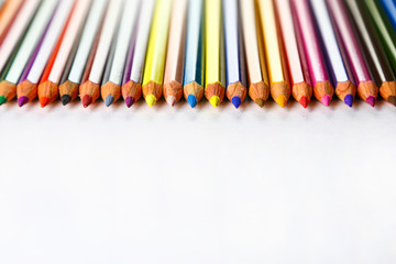 color pencils in row on white paper background