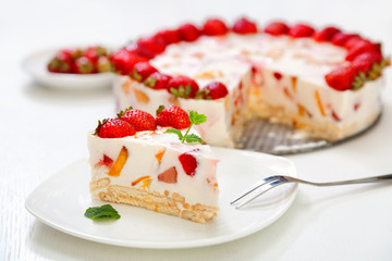 Cake with strawberries, gelly yogurt and cherries. Surface view. Isolated on white background. One piece in a white plate