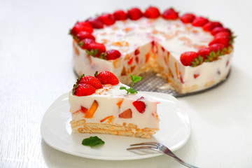 Cake with strawberries, gelly yogurt and cherries. Surface view. Isolated on white background. One piece in a white plate