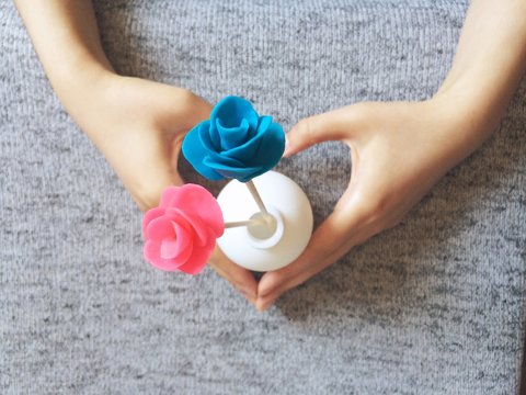 Heart shaped hands presenting playdough flowers
