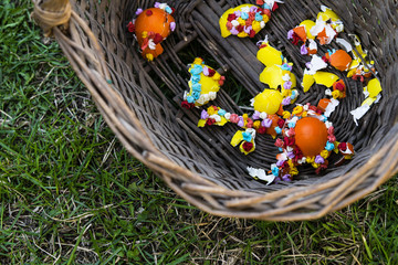 Easter basket with colored eggshells decorated patterns of crepe-paper standing on green grass 