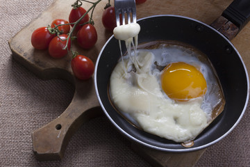 Fried eggs in a round pan wth cheese slices