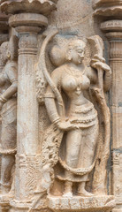 Trichy, India - October 15, 2013: Sandstone statue of dancing woman at Ranganathar Temple. Outside wall of old part built during Madurai Nayak era. Traditional dress and admiring parrot.