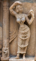 Trichy, India - October 15, 2013: Sandstone statue of woman looking at herself in handheld mirror at Ranganathar Temple. Outside wall of old part built during Madurai Nayak era.