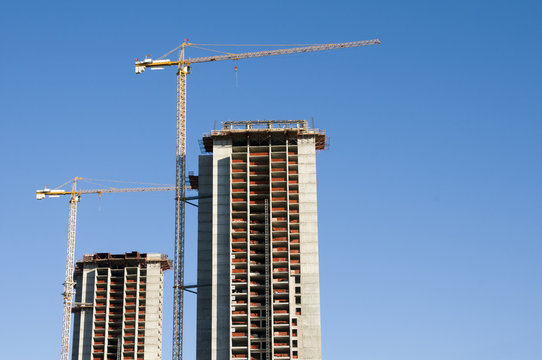Building under construction with cranes against the blue sky