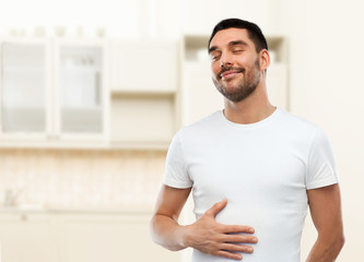 happy full man touching tummy over kitchen