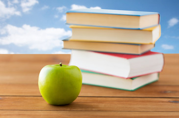 close up of books and green apple on wooden table