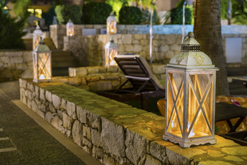 Romantic wooden lanterns adorn the stone walls in the beach area ,on the street one of the resort towns of Crete island at night.District of Rethymno.Greece.Europe.