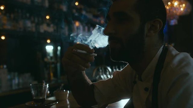 4K cinemagraph. Restaurant chef smoking a cigarette behind the bar. Motion photo seamless loop. Blackmagic URSA Mini