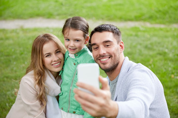 happy family taking selfie by smartphone outdoors
