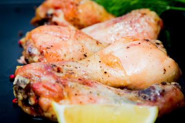 Roasted chicken legs with basil on the black background
