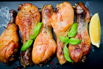 Roasted chicken legs with basil on the black background