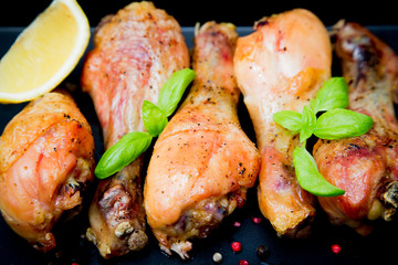 Roasted chicken legs with basil on the black background