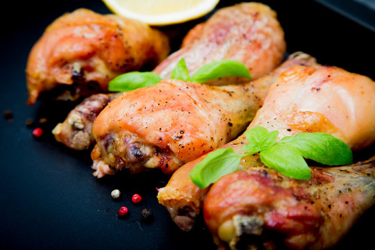 Roasted chicken legs with basil on the black background