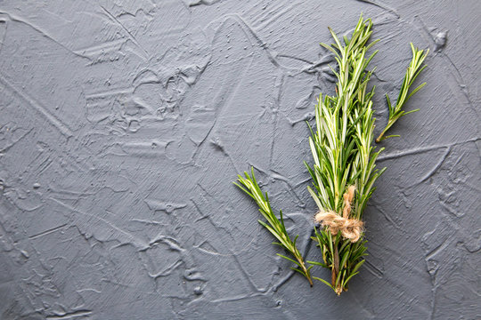Sprigs of rosemary tied with string on a dark gray background