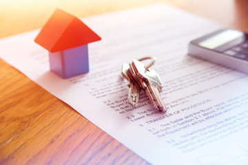 Wooden house miniature and house key lying on contract
