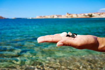 Hand holding stones at beach of Sardinia - Italy