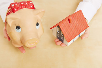 Hände halten Haus und Sparschwein