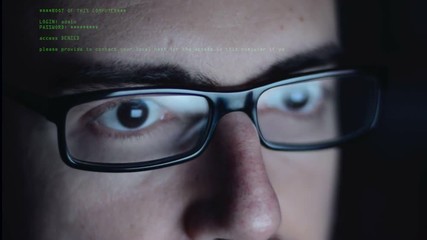 hacker  with glasses working in front of his computer monitor