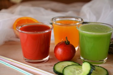 Three glasses of fresh smoothie with tomato, orange and cucumber.
