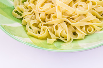 Close up of fettuccine pasta and olive oil in green plate isolated