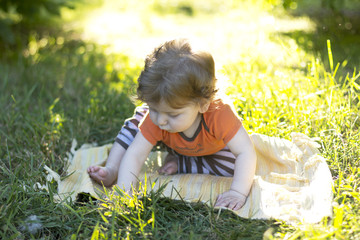 Beautiful child sitting in the green grass. Child outdoors. Children walk. Walk with the child. summer vacation
