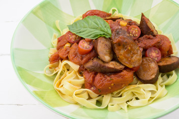 Chorizo sausage and tomato pasta meal with basil in plate isolat